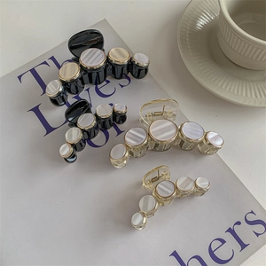 Elegant shell-textured hair clips in black and champagne on an open book background