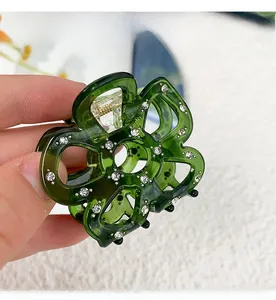 Macro shot of green acetate flower hair claw with sparkling rhinestones and gold spring