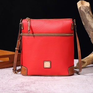 Detail of red lychee textured crossbody bag with brown trim on a vintage wood display