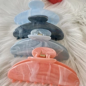 Detail view of marble pattern hair claws in pastel colors on white faux fur background