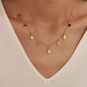 Detailed close-up of a gold star necklace with colorful beads on a knitted background
