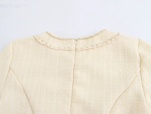 Macro detail of cream tweed dress back featuring an invisible zipper and braided neckline