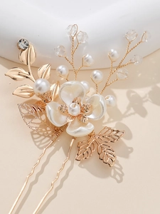Macro shot of bridal hair pin with golden leaves, pearls and crystal floral details
