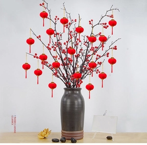Close-up of mini red flocked lanterns with gold strings and tassels on bonsai branches