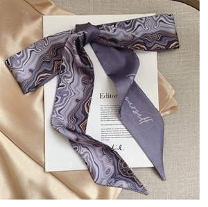Detail of purple marble silk scarf tied in a bow with elegant 'yourself' embroidery