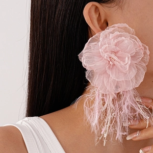 Close-up of pink tulle flower earrings with long fringe tassels on a female model