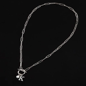 Silver paperclip necklace with letter K pendant and pearl on black background