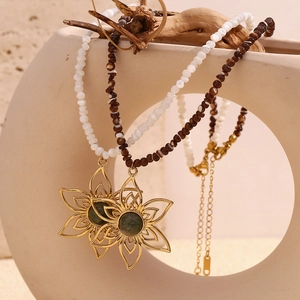 Detail of flower pendants with green stones on white and brown beaded necklaces