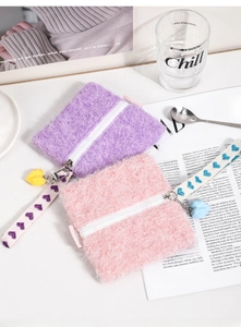 Detail of plush square coin purses in purple and pink with heart straps on a white desk