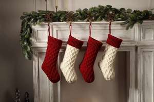 Details von rot-weißen Strick-Weihnachtssocken mit Karomuster, die am Kamin aufgehängt sind