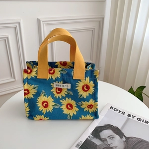 Detail of sunflower canvas lunch bag featuring bright yellow handles and floral pattern