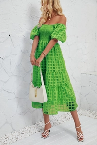 Detailed close-up of smocked bodice and tiered mesh fabric on a green A-line dress