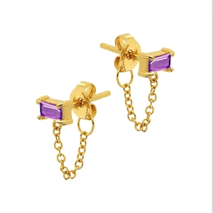 Macro detail of gold-plated chain earrings featuring rectangular pink zircon gemstones