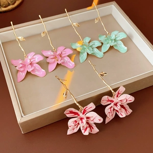 Detailed shot of three vintage enamel flower earrings in pink and mint green finishes