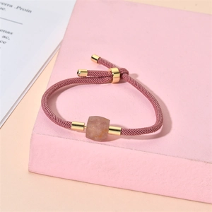 Détail d'un bracelet en corde tressée rose avec fermoir doré réglable et perle carrée