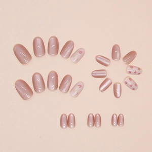 Detail of cat eye bow press-on nails featuring cute strawberry patterns and peach pink finish