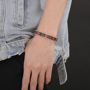 Detail of silver bike chain bracelet with red crystals on denim jacket sleeve