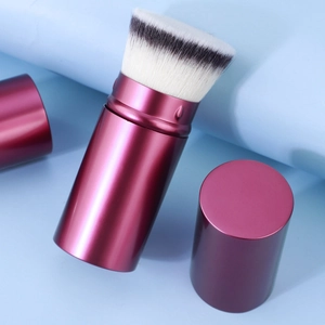 Retractable makeup brush with synthetic bristles and metallic magenta handle and cap