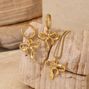 Golden bowknot jewelry set including necklace and earrings displayed on stone base