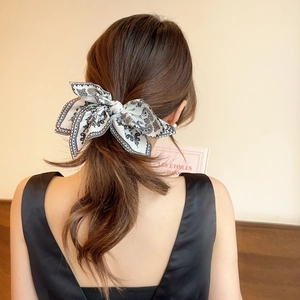 Detail of vintage paisley pattern hair scarf tied in a bow on a ponytail accessory