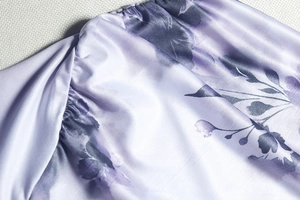 Détail macro du motif tie-dye floral violet sur satin soyeux avec ourlet froncé