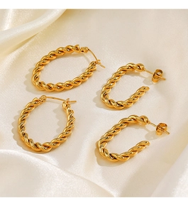Vue détaillée de boucles d'oreilles torsadées en or sur un fond de soie plissée chic