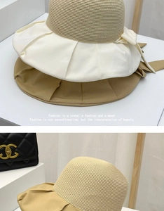 Close-up of summer straw sun hat detail featuring pleated fabric brim and large bow knot