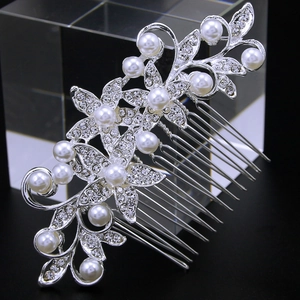 Detail of silver bridal hair comb with pearls and rhinestones on a dark reflective surface