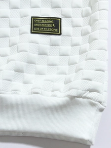 Detail of white waffle knit sweatshirt featuring textured fabric and brand chest patch