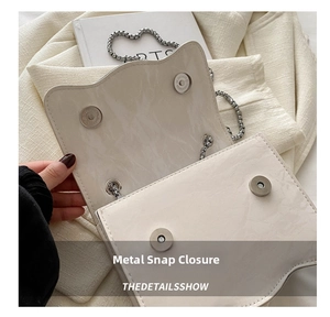 Detail of silver magnetic buckle closure on a beige leather crossbody bag for women