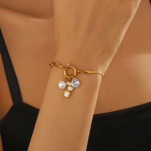 Gold-plated stainless steel charm bracelet with pearls and blue teardrop stones on a model