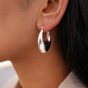 Close-up of polished silver teardrop earrings worn by a model for a modern fashion look