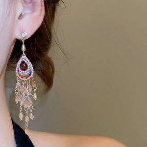 Close-up of sparkling waterdrop tassel earrings with colorful crystals and gold chains