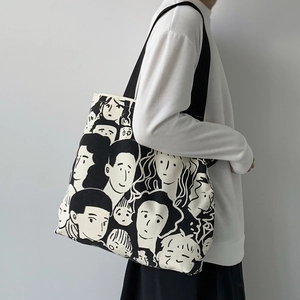 Dettaglio della borsa tote in tela color crema con illustrazioni artistiche di volti in bianco