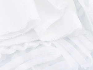 Detailed close-up showing white fabric stitching and mesh lace texture on dress hem