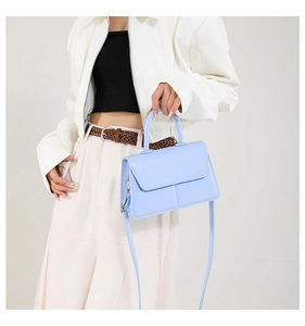 Light blue PU leather handbag with top handle and crossbody strap shown on a model