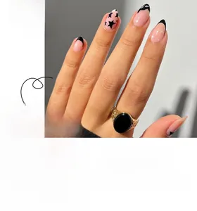 Short almond press-on nails featuring pink base with black stars and French tips