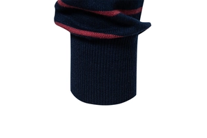 Detail of navy blue knit sweater sleeve showing red stripes and ribbed cuff craftsmanship