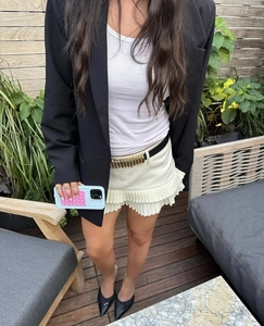Foto de estilo callejero de minifalda plisada blanca con cinturón negro y hebilla metálica