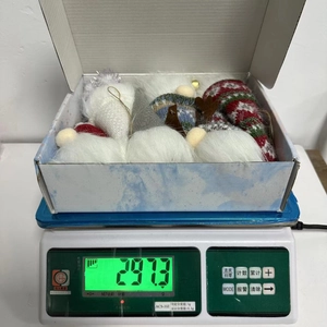Gnome plush Christmas ornaments set inside a box being weighed on a scale at 297.3g