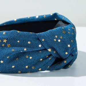 Detail of blue denim headband with gold stars and central knot design macro