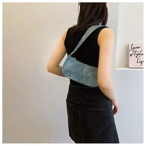Détail du sac sous le bras en denim bleu avec rivets argentés sur la bandoulière