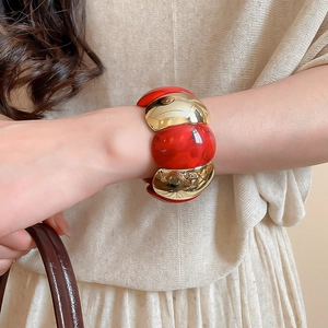 Detail shot of chunky red marble resin and gold metal link bracelet on a woman's wrist