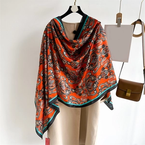 Écharpe en soie orange à motif paisley avec bordure noire drapée sur un manteau