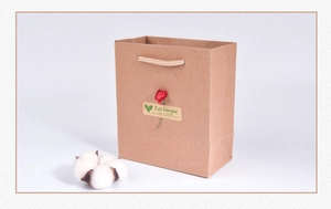 Close-up of brown kraft paper gift bag featuring a decorative floral sticker and cotton