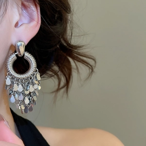 Close-up of vintage silver geometric tassel earrings with leaf-shaped metal pendants