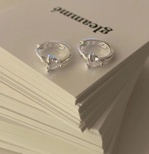 Detail of silver heart-shaped pendant hoop earrings featuring sparkling cubic zirconia stones