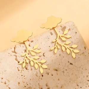Detailed view of golden leaf drop earrings on a textured stone with soft lighting