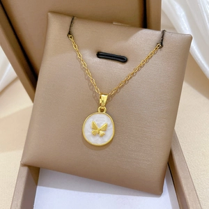 Macro shot of gold butterfly necklace pendant with white round inlay on display stand