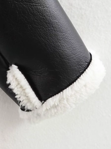 Detail of black leather sleeve cuff featuring soft white faux shearling lining texture